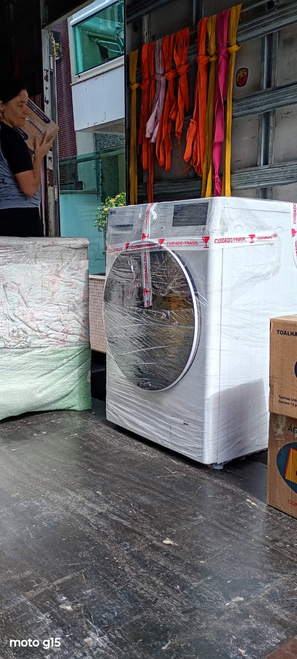 Máquina de lava e seca plastificada e lacrada dentro do baú, com as cintas de amarração penduradas