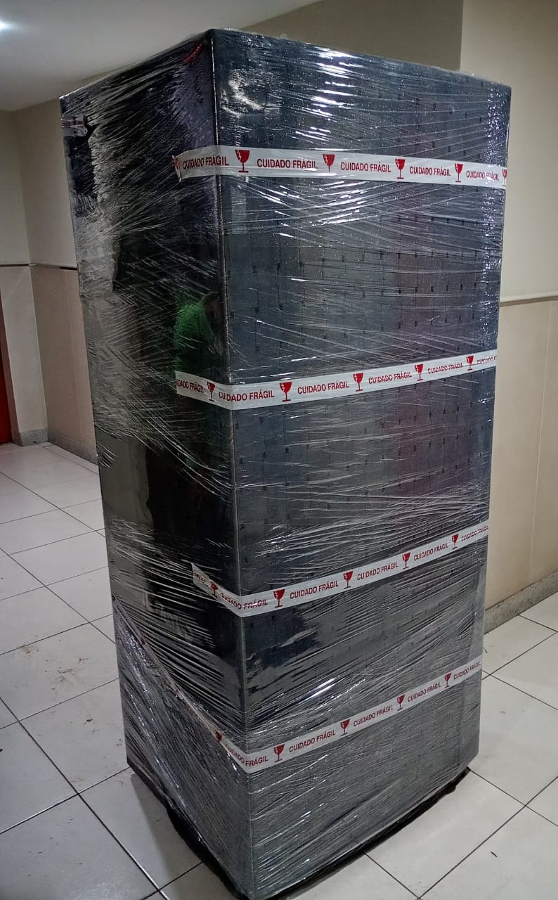 Geladeira envolta em filme plástico com várias voltas de fita de cuidado frágil